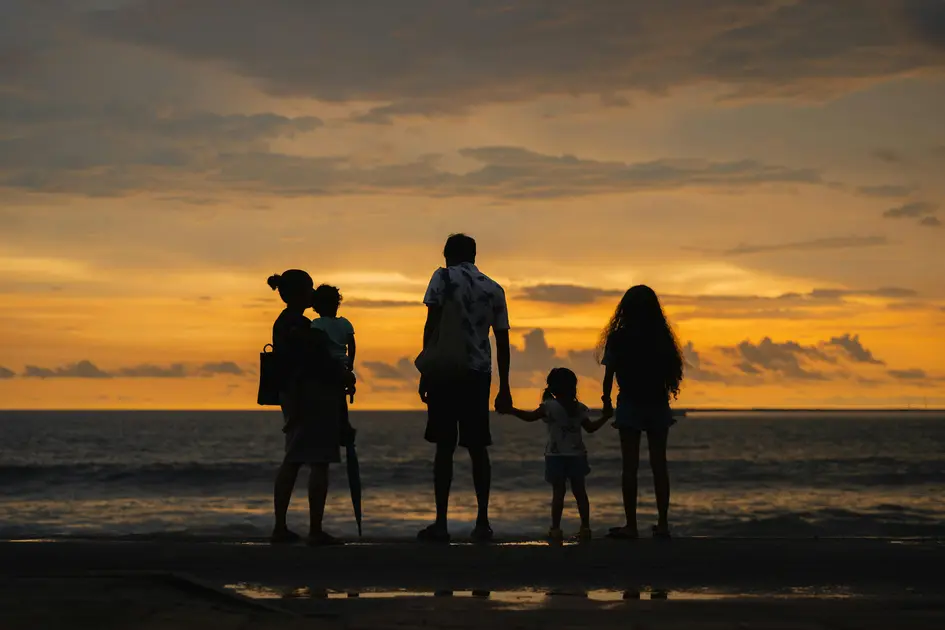 Silhouette of a family standing by the ocean at sunset in Sri Lanka, looking out together